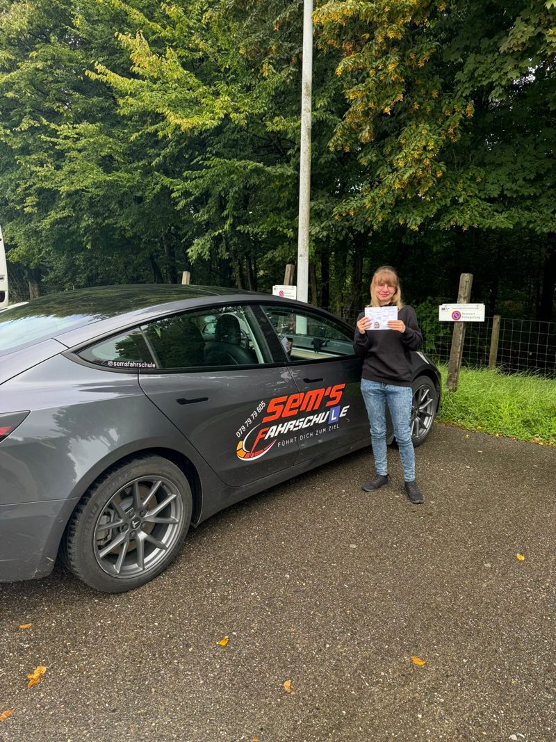 Fahrschülerin mit bestandener Prüfung am Tesla Model 3